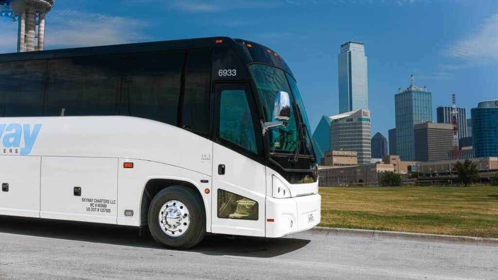 Charter bus parked in front of downtown Dallas skyline on a sunny day