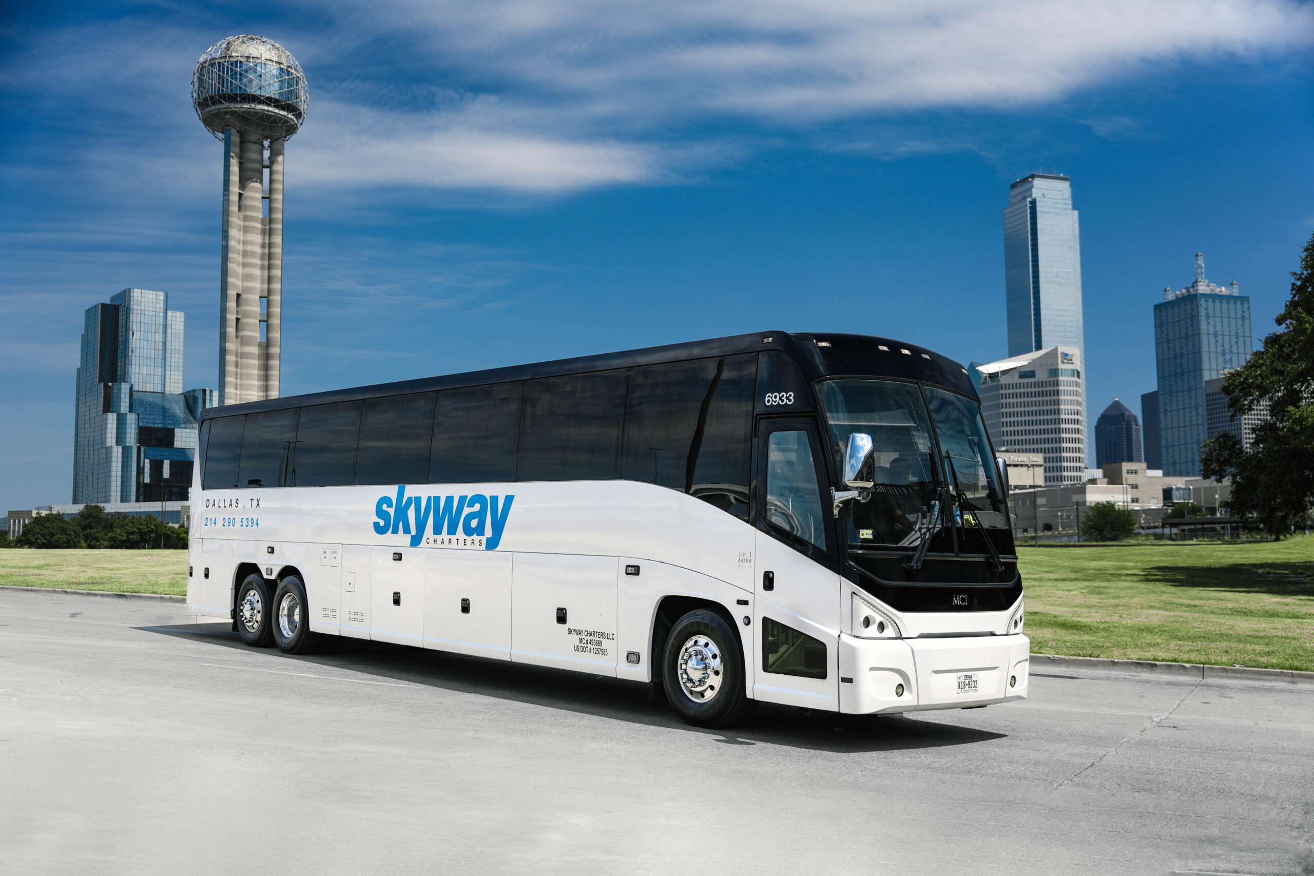 Skyway Charters bus parked in front of Reunion Tower and downtown Dallas skyline on a clear day